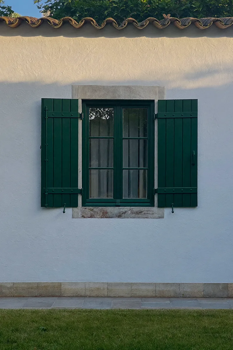 Illustration: White rendered villa wall with green wooden shutters